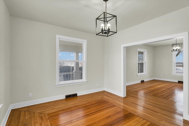 spare room featuring hardwood / wood-style floors and an inviting chandelier