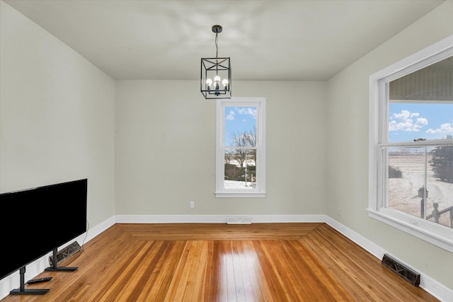 unfurnished dining area with hardwood / wood-style flooring and an inviting chandelier