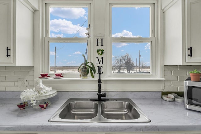 details with white cabinetry, light stone countertops, sink, and tasteful backsplash