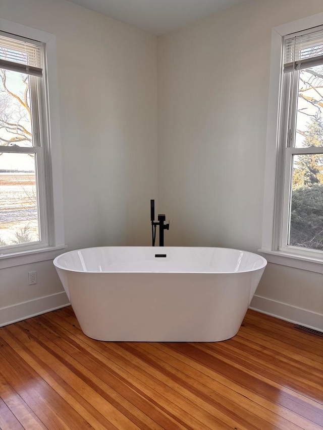 bathroom with hardwood / wood-style flooring, a healthy amount of sunlight, and a washtub