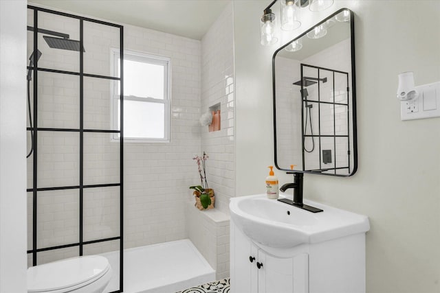 bathroom featuring vanity, a tile shower, and toilet