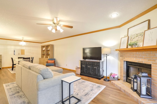 living room with crown molding, light hardwood / wood-style floors, a brick fireplace, and a textured ceiling