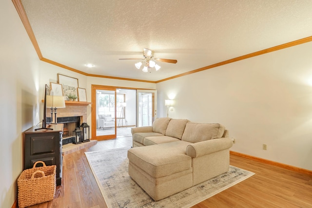 living room with ceiling fan, ornamental molding, a textured ceiling, and light wood-type flooring