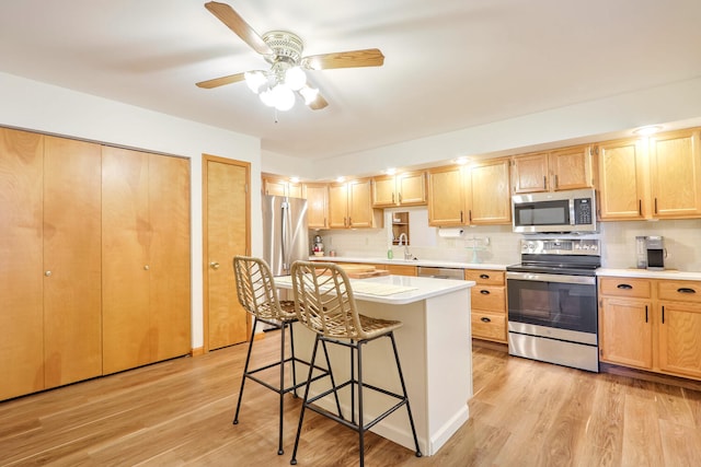 kitchen featuring a kitchen bar, light hardwood / wood-style flooring, a center island, and appliances with stainless steel finishes