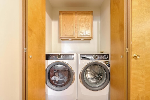 clothes washing area featuring cabinets and separate washer and dryer