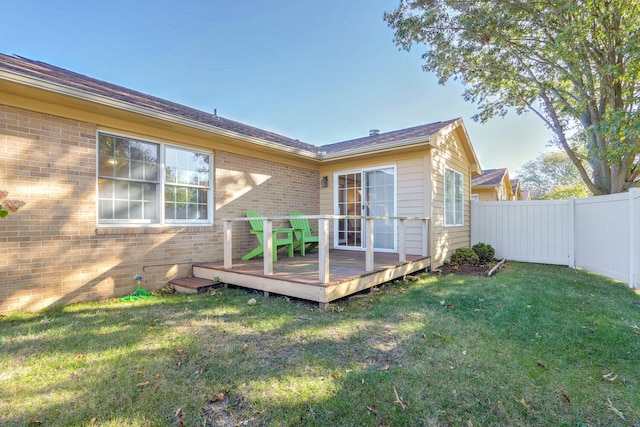 rear view of property featuring a wooden deck and a lawn