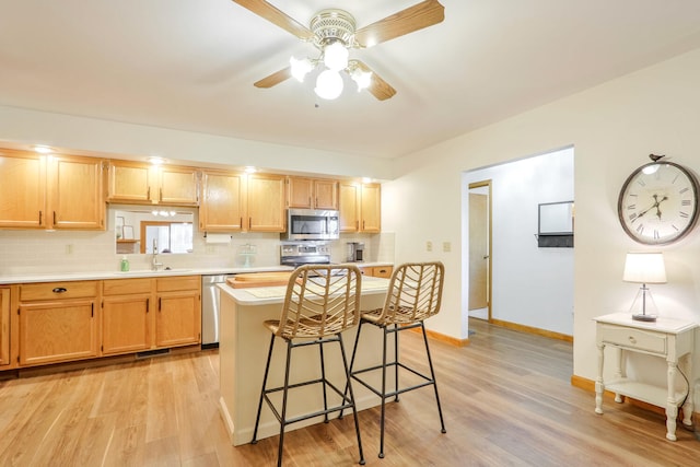 kitchen with stainless steel appliances, a kitchen island, a breakfast bar area, and light hardwood / wood-style floors