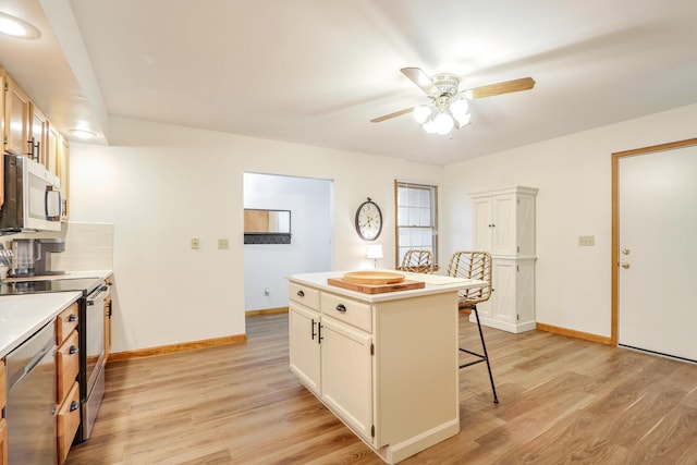 kitchen with a breakfast bar, light wood-type flooring, appliances with stainless steel finishes, a kitchen island, and decorative backsplash