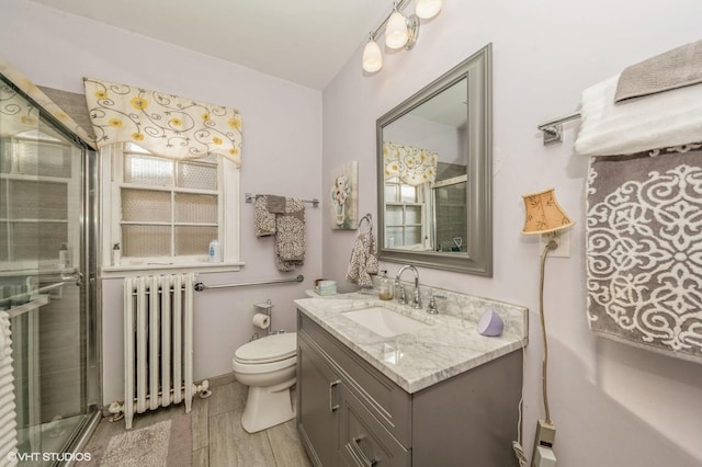 bathroom with radiator heating unit, toilet, an enclosed shower, and vanity