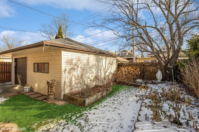 snow covered property with a garage and an outdoor structure