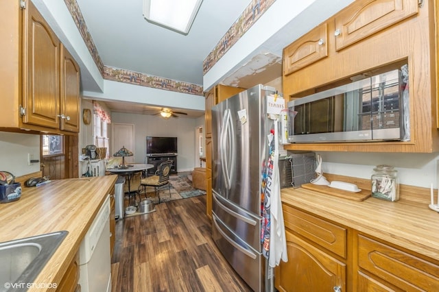 kitchen with sink, stainless steel refrigerator, ceiling fan, white dishwasher, and dark hardwood / wood-style flooring