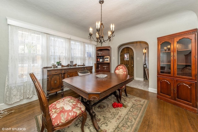 dining room with an inviting chandelier, dark hardwood / wood-style floors, and a textured ceiling