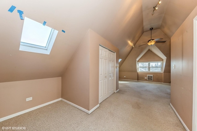 bonus room with lofted ceiling with skylight, light colored carpet, and ceiling fan