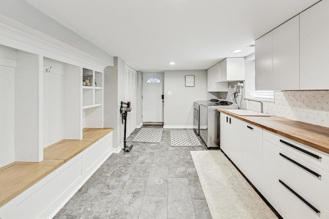 kitchen with backsplash, separate washer and dryer, white cabinets, and wooden counters