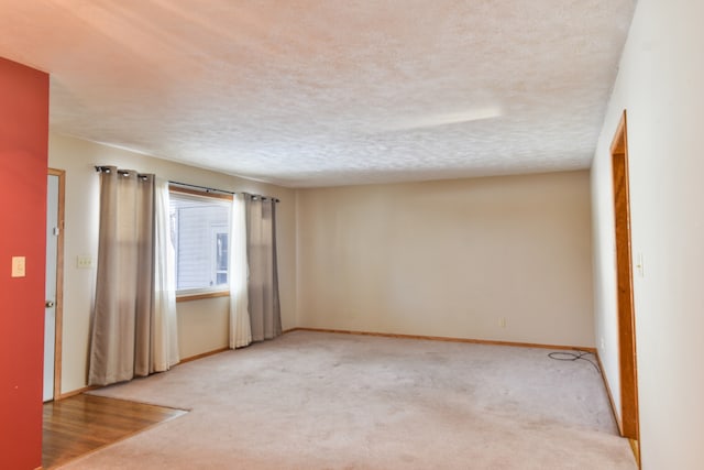 empty room with light carpet and a textured ceiling