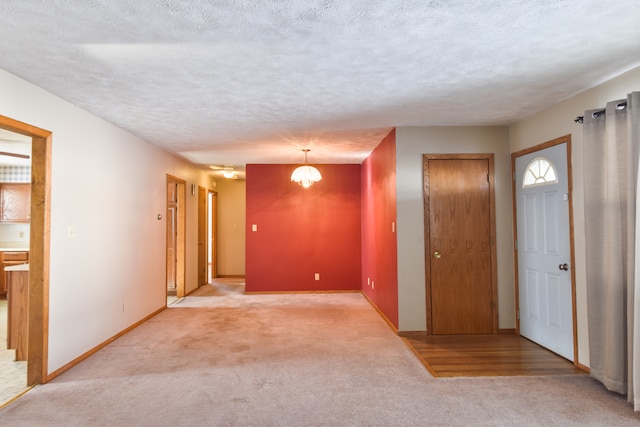 carpeted spare room featuring a textured ceiling and a chandelier