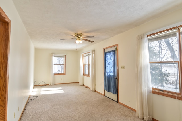 empty room featuring ceiling fan, light colored carpet, and a textured ceiling