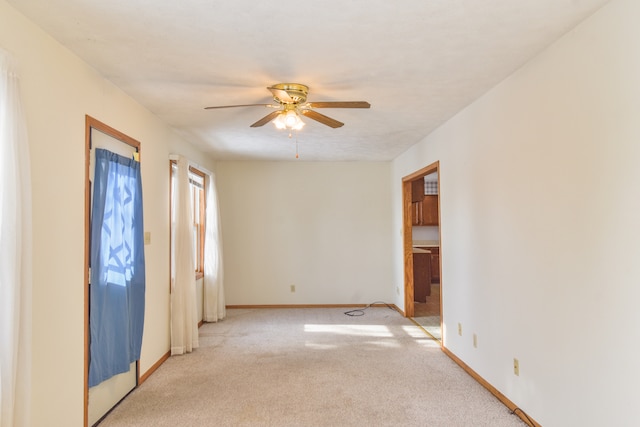 spare room with ceiling fan and light carpet