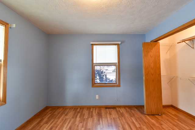 unfurnished bedroom featuring light hardwood / wood-style flooring, a closet, and a textured ceiling