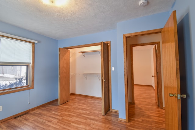 unfurnished bedroom featuring a textured ceiling, a closet, and light wood-type flooring