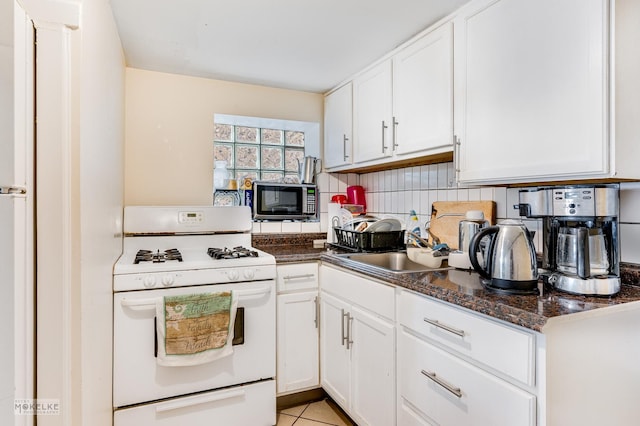 kitchen with white cabinets, decorative backsplash, light tile patterned flooring, and white range with gas cooktop