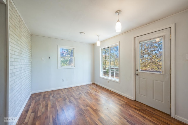 foyer entrance with dark hardwood / wood-style floors and brick wall