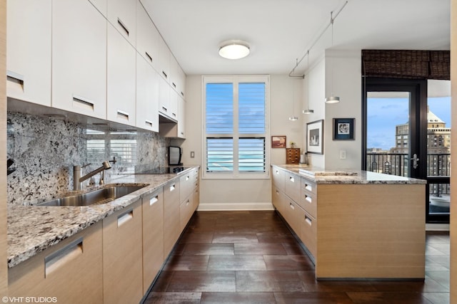 kitchen featuring sink, light stone counters, and kitchen peninsula