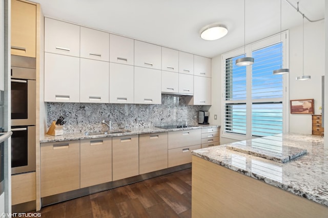 kitchen featuring sink, light stone counters, backsplash, hanging light fixtures, and black electric stovetop