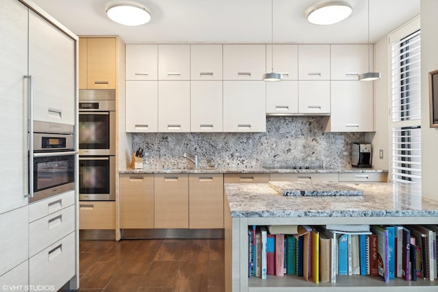 kitchen with light stone counters, decorative backsplash, black electric stovetop, double oven, and white cabinets