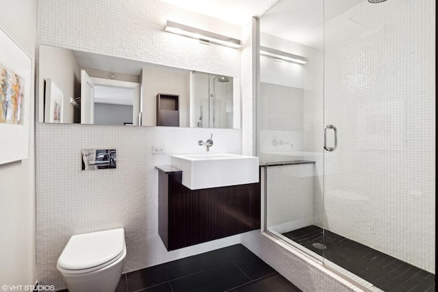 bathroom featuring toilet, vanity, tile patterned floors, tile walls, and a shower with door