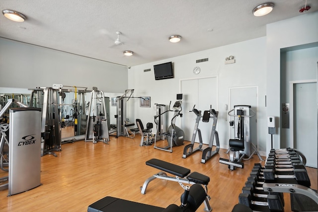 gym with wood finished floors and a textured ceiling