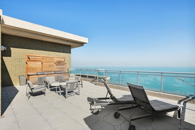 view of patio / terrace featuring a balcony, a water view, and an outdoor living space