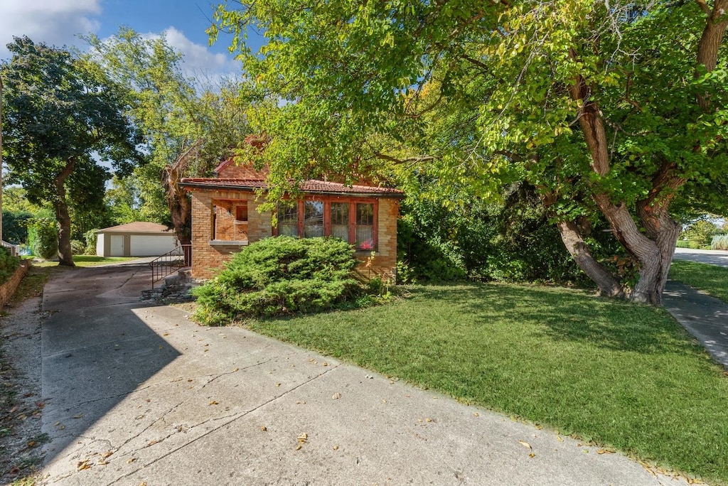 view of front of property featuring an outbuilding, a front lawn, and a garage