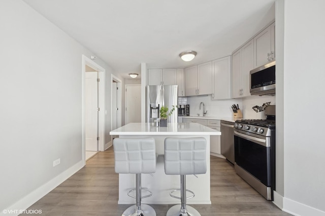 kitchen featuring appliances with stainless steel finishes, a breakfast bar, sink, light hardwood / wood-style flooring, and a center island