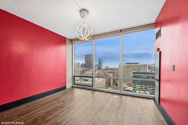 spare room featuring expansive windows, hardwood / wood-style floors, and a notable chandelier