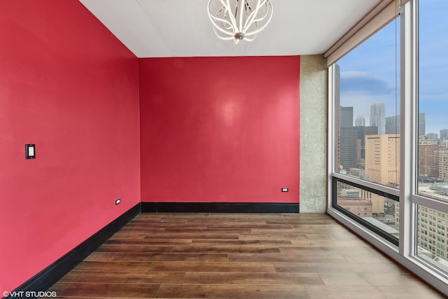 unfurnished room featuring floor to ceiling windows, dark hardwood / wood-style flooring, and a chandelier