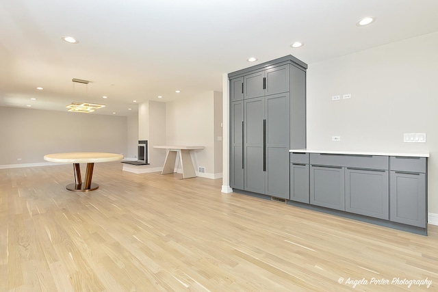 kitchen with gray cabinets, light hardwood / wood-style flooring, and hanging light fixtures