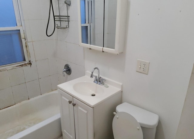 full bathroom featuring vanity, tiled shower / bath combo, and toilet