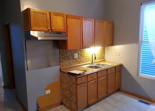 kitchen with decorative backsplash, sink, and light hardwood / wood-style flooring