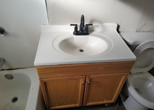 bathroom featuring a tub, vanity, and toilet