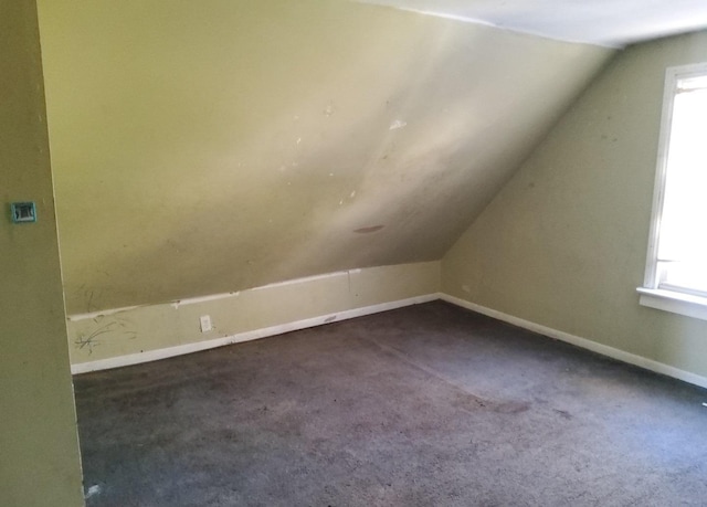 bonus room with plenty of natural light, dark carpet, and lofted ceiling