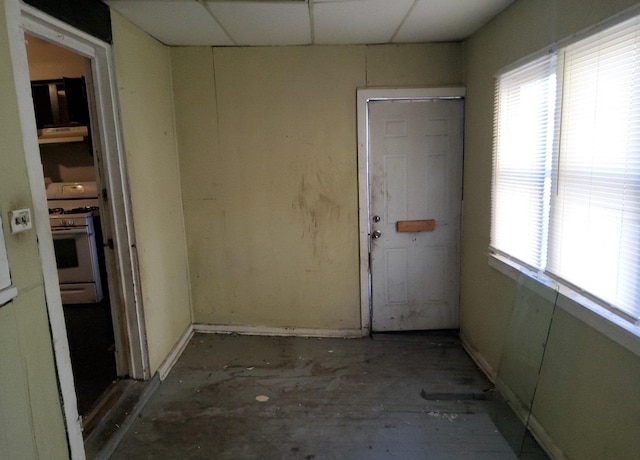 empty room with a paneled ceiling and concrete flooring