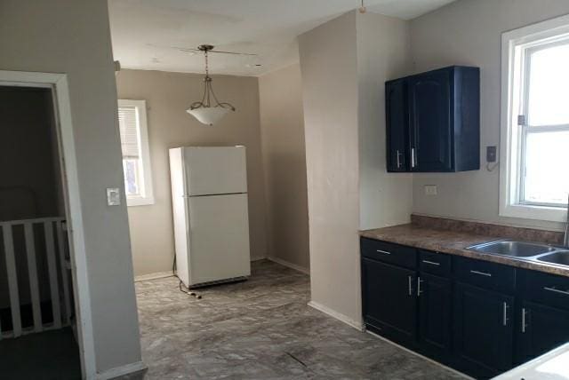 kitchen featuring a wealth of natural light, blue cabinets, sink, pendant lighting, and white refrigerator