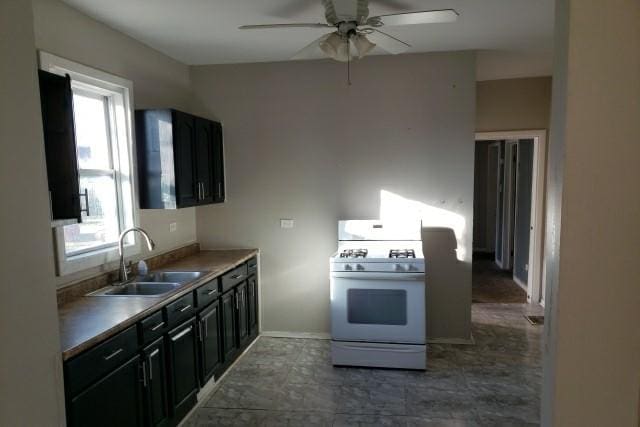 kitchen with ceiling fan, white range with gas stovetop, and sink