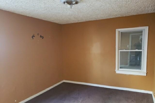 carpeted empty room featuring a textured ceiling