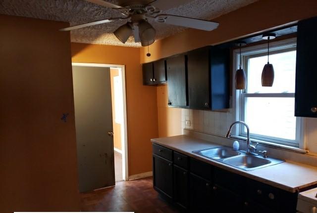 kitchen with a textured ceiling, sink, a healthy amount of sunlight, and decorative light fixtures