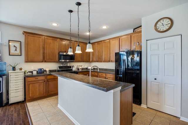 kitchen with appliances with stainless steel finishes, decorative light fixtures, dark stone countertops, a kitchen island with sink, and light tile patterned floors