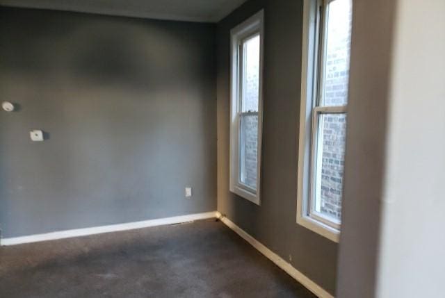 spare room featuring dark colored carpet