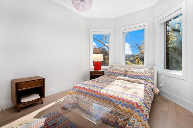 bedroom with hardwood / wood-style floors, multiple windows, and crown molding