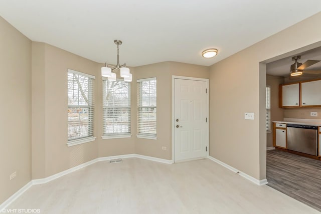 spare room with a chandelier, a wealth of natural light, and light hardwood / wood-style flooring